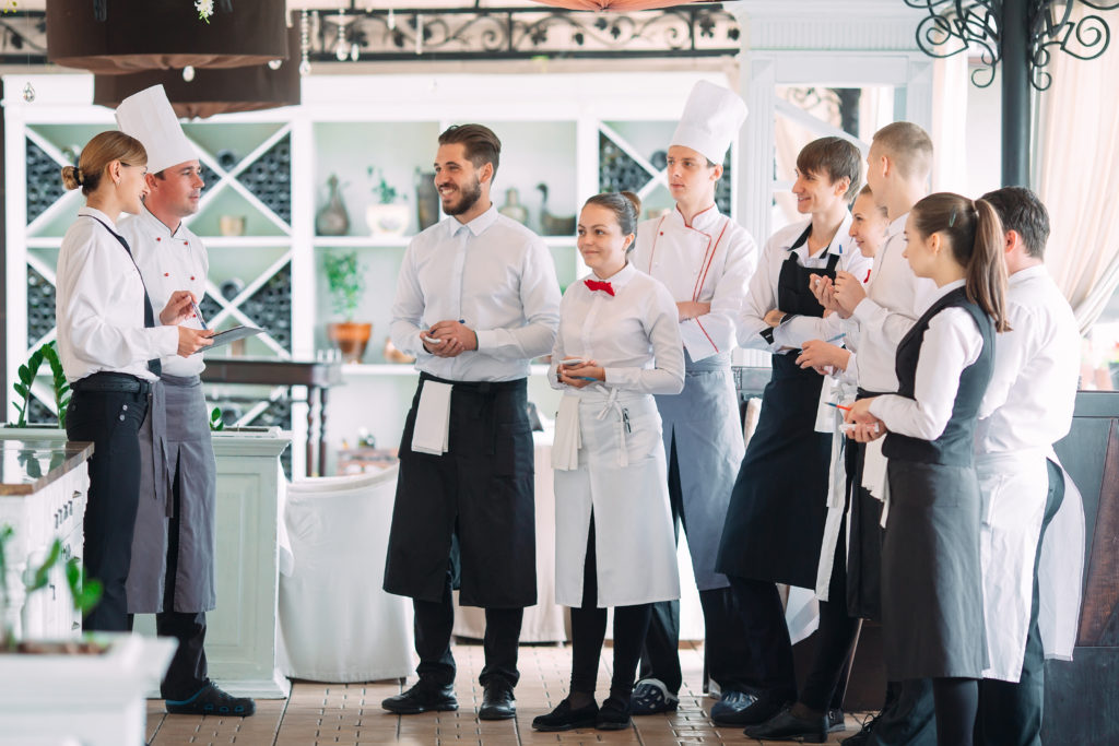 Le gérant du restaurant et son personnel sur la terrasse, en train d'échanger avec le chef de cuisine.